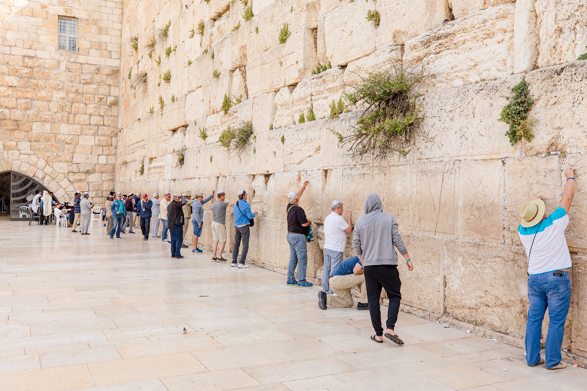 A diverse group of people engaged in prayer and reflection at the Western Wall.