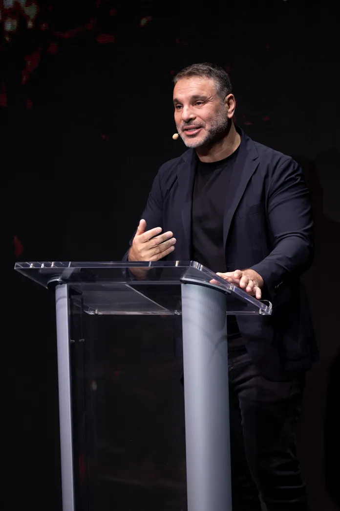 Amir Tsarfati speaking at a podium on stage