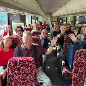 Waving travelers sitting together on a tour bus